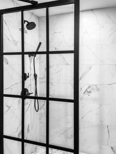 a bathroom with a shower with white marble walls at The Phenix, Historic DTWN Hotel, Market Square View, King Bed, Room # 400 in Bangor