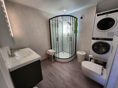 een badkamer met een douche, een wastafel en een wasmachine bij Igerøya in Mo