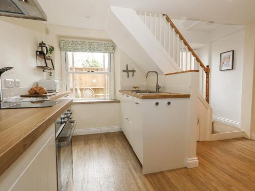 a kitchen with a sink and a staircase at Bobbin Cottage in Swanage