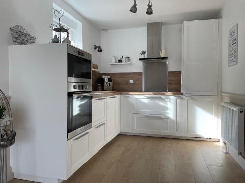 una cucina bianca con elettrodomestici bianchi e pavimenti in legno di Un air de campagne a Châtenois