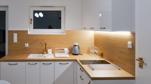 a kitchen with white cabinets and a sink and a microwave at Goldfin apartments in Ustka