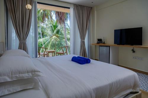 a bedroom with a large white bed and a large window at Kinan Boutique in Fulidhoo