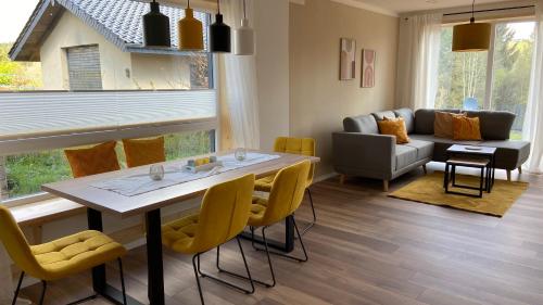 a living room with a table and yellow chairs at Urlaub am Schwarzbach mit Sauna und Whirlpool Haus Felix in Küchelscheid