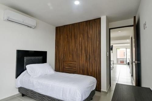 ein Schlafzimmer mit einem weißen Bett und einer Holztür in der Unterkunft Beautiful Apt Near the Beach in Boca del Río