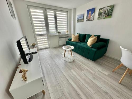 uma sala de estar com um sofá verde e uma mesa em Apartament Sobolewski em Sandomierz