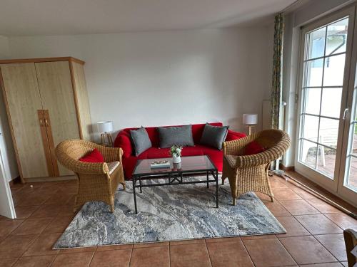 - un salon avec un canapé rouge et des fauteuils en osier dans l'établissement Auszeit-mit-Kind-und-Hund, à Sagard