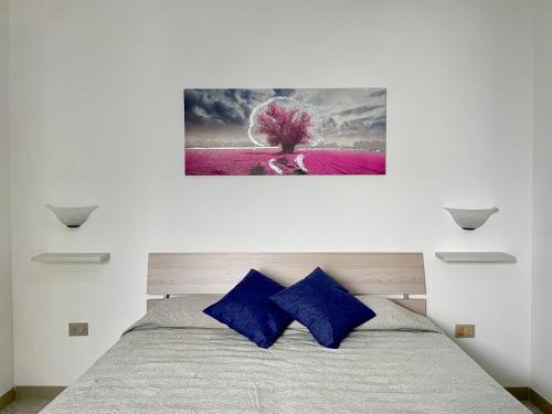 a bedroom with a bed with two blue pillows at Casa Ermes - Piano terra indipendente fronte spiaggia, ampio spazio esterno attrezzato in Marina di Pescoluse