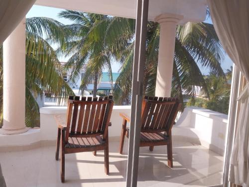 two chairs and a table on a porch with palm trees at El Paraíso de Capitán Fernando in Chelem
