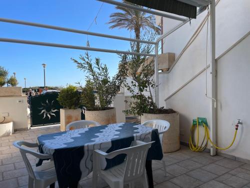 a table and chairs on a patio with a palm tree at Casa Ermes - Piano terra indipendente fronte spiaggia, ampio spazio esterno attrezzato in Marina di Pescoluse