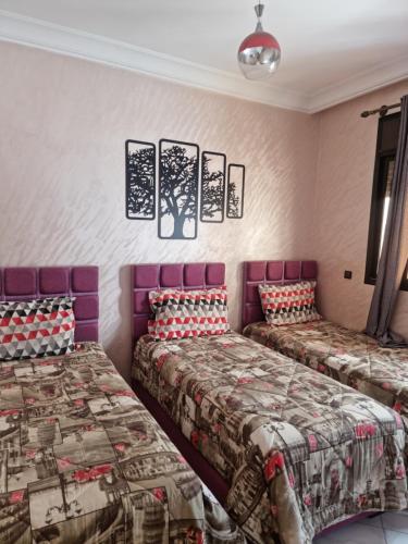 two beds in a room with pink walls at Apprt Ennakhil 1 in El Jadida
