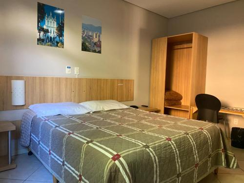 1 dormitorio con 1 cama con edredón verde en CHA Mime Hotel, en Blumenau