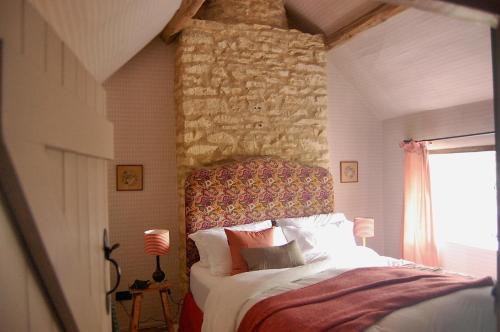 a bedroom with a bed with a stone wall at Little Cottage Shipton in Shipton under Wychwood