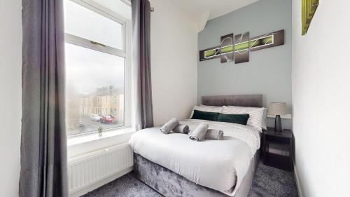 um quarto com uma cama e uma janela em Modernised 3-bedroom Blackburn townhouse sleeps 6 em Rishton