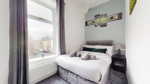 a bedroom with a bed and a window at Modernised 3-bedroom Blackburn townhouse sleeps 6 in Rishton