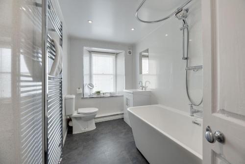 a white bathroom with a tub and a toilet at Salvin House Alston in Alston