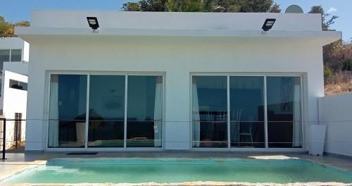 Biały dom ze szklanymi drzwiami i basenem w obiekcie VILLA FLEUR d'EBENE w mieście Antsakomboena