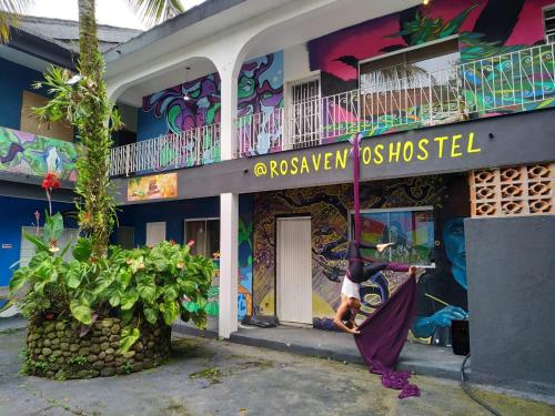 Rosa dos Ventos Hostel في بويكوكانجا: امرأة تقف خارج المبنى مع لوحة جدارية