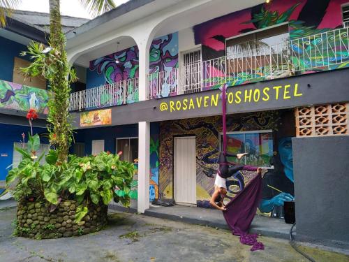 una donna in piedi fuori da un edificio con un murale di Rosa dos Ventos Hostel a Boicucanga