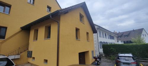 a yellow building with a motorcycle parked next to it at Gästehaus Spring Herznach in Herznach