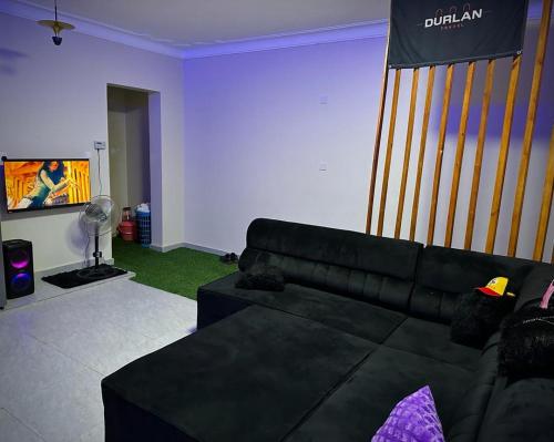 a living room with a black couch and a tv at Durlan metroplex in Kampala