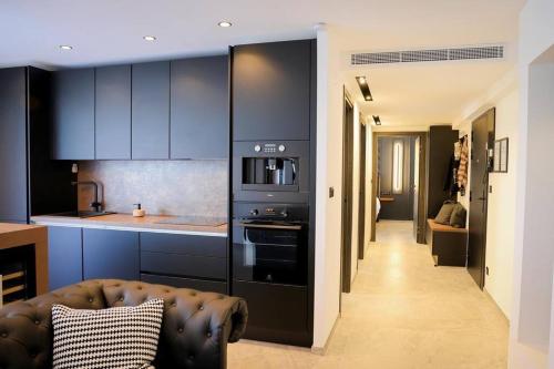 - une cuisine avec des armoires noires et un canapé dans la chambre dans l'établissement Blancs de blancs, à Cannes