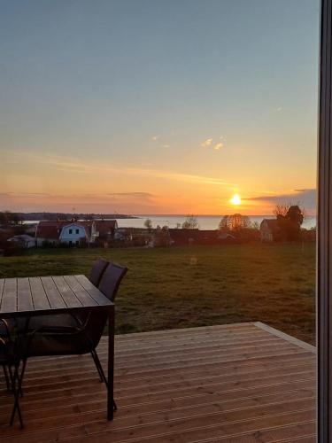 a sunset from a deck with a table and a field at Klinta sea view 2 in Köpingsvik