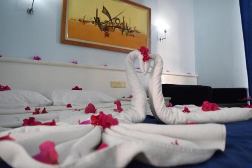 a bed with white towels and red flowers on it at Ares Blue Hotel in Kemer