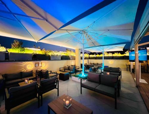 um pátio no último piso com sofás, mesas e um guarda-chuva em Romoli Hotel em Roma
