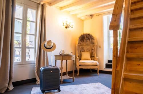 サン・レミ・ド・プロヴァンスにあるHôtel Gounodのスーツケースと椅子、窓が備わる客室です。