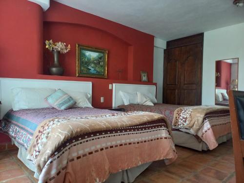 2 camas en una habitación con paredes rojas en SOLACHE INN, en Zitácuaro