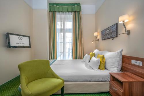 a hotel room with a bed and a chair at Hotel President in Budapest