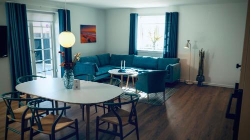 a living room with a couch and tables and chairs at Plesners Badehotel-Lejligheder in Skagen