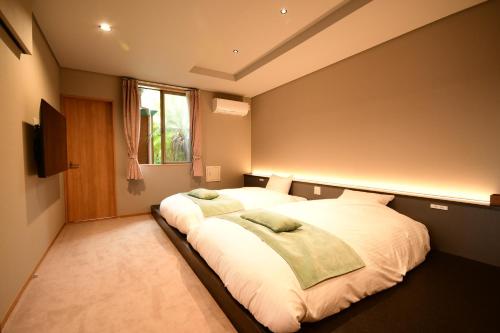 a bedroom with two beds and a flat screen tv at 鵜原館 -Ubarakan- in Katsuura