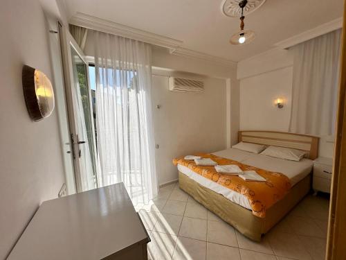 a bedroom with a bed and a table and a window at Suit Fiona in Fethiye