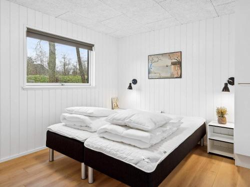 a bedroom with a bed with white sheets and a window at Holiday home Henne VI in Henne Strand