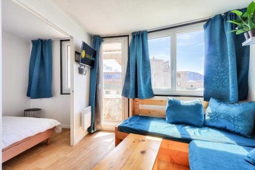 - une chambre avec un canapé bleu et une grande fenêtre dans l'établissement Résidence Les Alpages - maeva Home - Appartement 2 pièces 5 personnes - Sélection MAE-2944, à Morzine