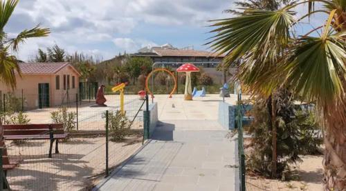 einen Park mit einem Spielplatz mit einer Bank und Palmen in der Unterkunft Camping Les Pins maritimes in Hyères
