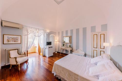a bedroom with a white bed and a chair at Villa Mary Suites in Positano