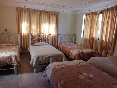 una habitación de hotel con 3 camas y cortinas en HoSTAL SANTA BARBARA en Torotoro