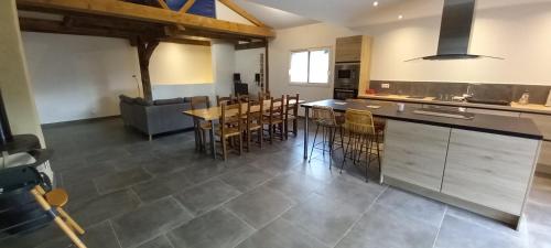een keuken en een woonkamer met een tafel en stoelen bij Le gîte des Oliviers in Meyras