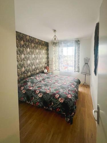 a bedroom with a bed with a floral bedspread at Tram C La belle Rose Logement proche Gare Bordeaux in Bègles