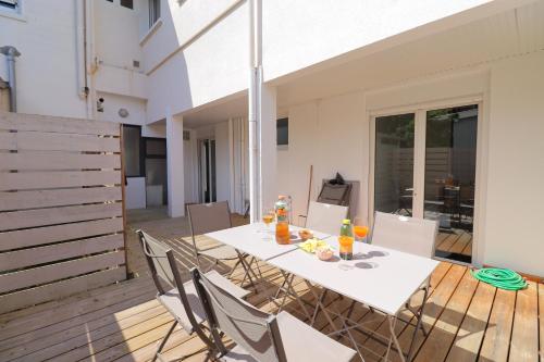 une table blanche et des chaises sur une terrasse dans l'établissement Le Spazioso - T3 Arcachon avec terrasse privative, à Arcachon