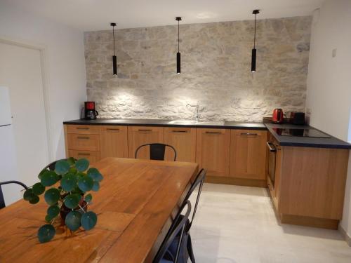 cocina con mesa de madera y pared de piedra en Maison de Vacances - jardin - Wifi, en Ornans