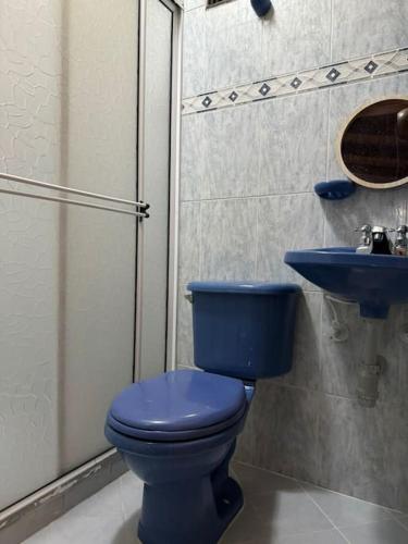 La salle de bains est pourvue de toilettes bleues et d'un lavabo. dans l'établissement Acogedor apartamento con calor de hogar, à Envigado