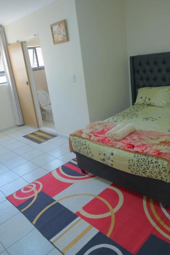 1 dormitorio con cama y alfombra en el suelo en SUPA LODGE, en Parow