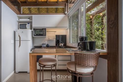 a kitchen with a refrigerator and a counter with stools at VGZ - Cabanas charmosas entre Barra de Ibiraquera e Rosa in Imbituba