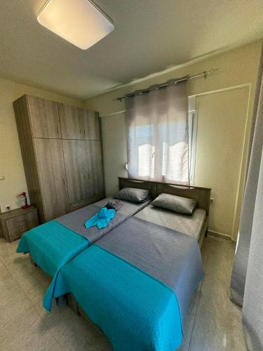 a bedroom with a blue bed and a window at Adoniss Apartmentss in Paralia Dionysiou