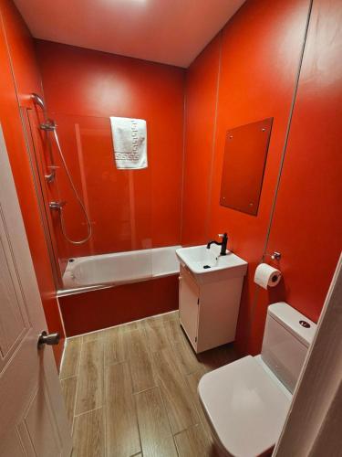 a bathroom with orange walls and a sink and a tub at Nysdill Accommodation Ltd in Norwich