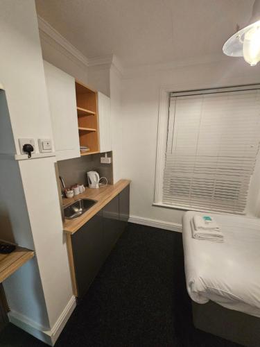 um pequeno quarto com um lavatório e uma cama em Nysdill Hotel Norwich em Norwich