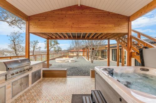 an outdoor kitchen with a hot tub and a deck at Guadalupe Bluff Modern House in Kerrville